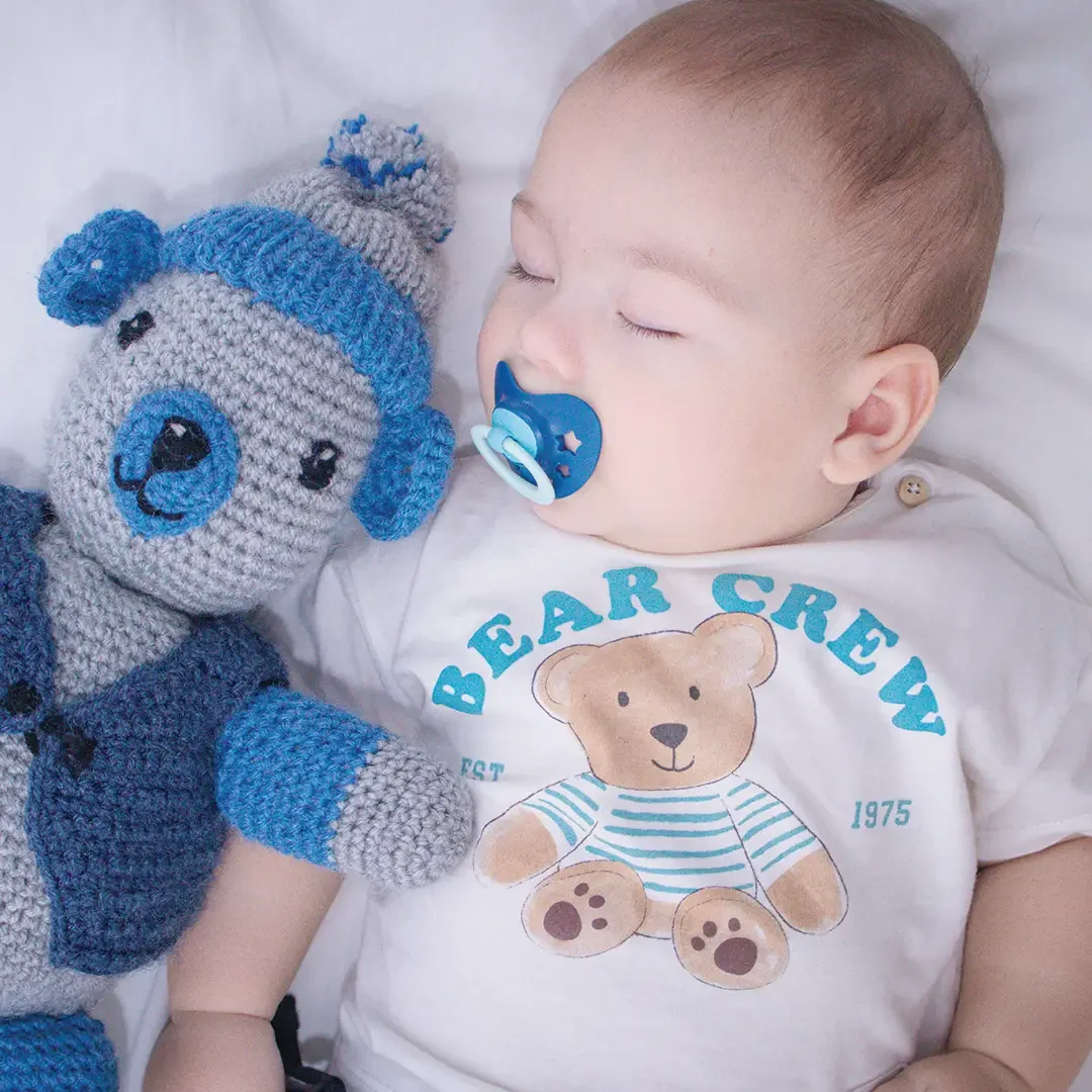 Sleeping baby beside a handmade teddy bear